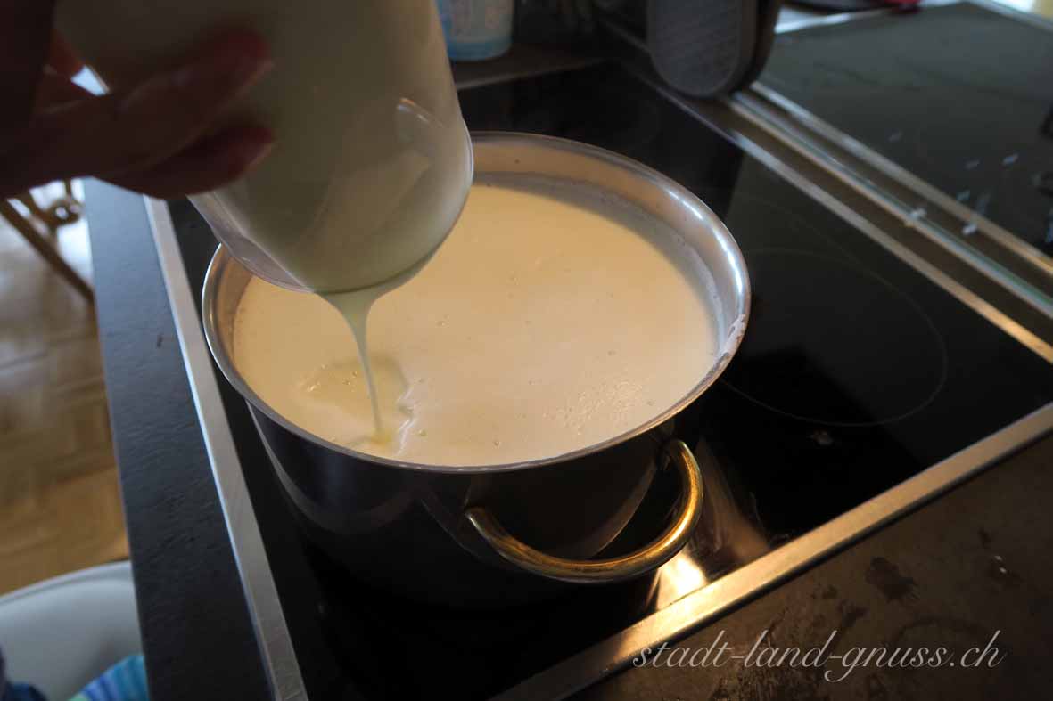 Milch vom Herd nehmen und dann 3,5dl Joghurt und Zitronensaft zugeben. Ein grobmaschiges Sieb mit einem Mulltuch auslegen und in ein grosses Becken stellen.